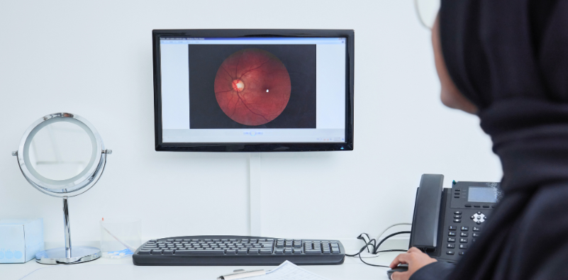 An optometrist reviewing a retinal image on the computer at the opticians