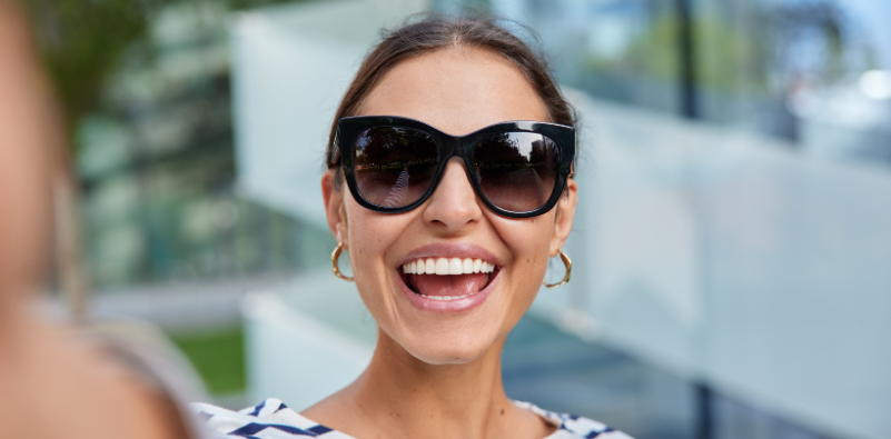 A woman taking a selfie, wearing a pair of black, oversized cat-eye sunglasses.