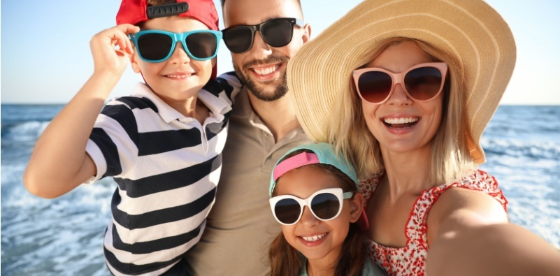A family at the beach wearing sunglasses.