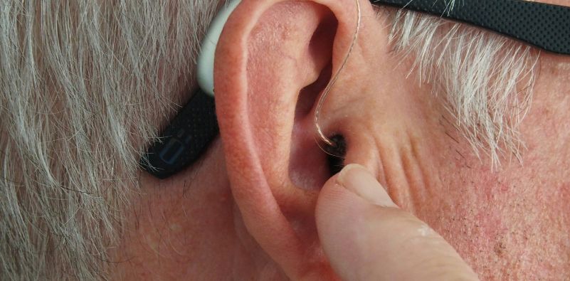An old man’s ear with hearing aids on
