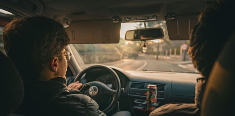 2 men in a car with the camera focused on the driver wearing glasses